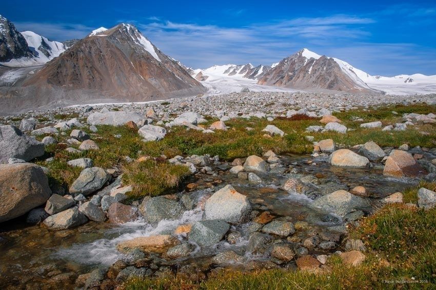 Snow-covered peaks, glacier and a rocky alpine stream in Altai Tavan Bogd.