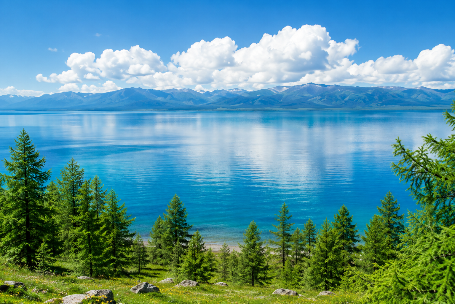 Khuvsgul Lake with clear blue water, forested shore, and mountain horizon.